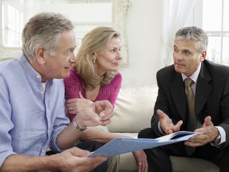 Mature couple sitting on sofa with financial advisor. Mature couple sitting on sofa with financial advisor