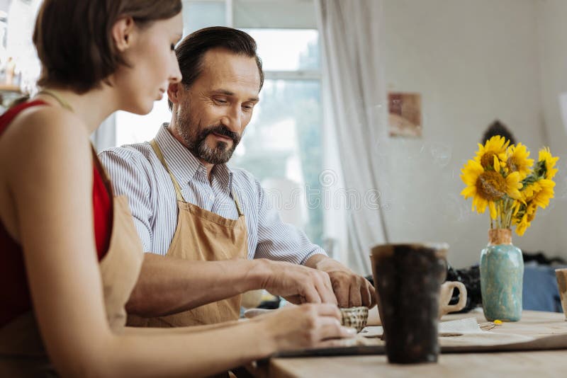 Paare von den Ceramists, die am Tisch mit Vase mit Sonnenblumen sitzen lizenzfreie stockfotos Paare von den Ceramists, die am Tisch mit Vase mit Sonnenblumen sitzen lizenzfreie stockfotos