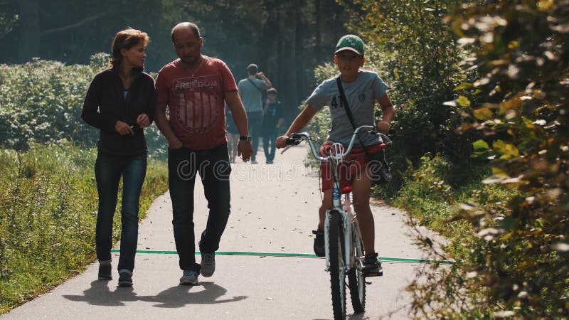 Paargangen langs weg in park Het roken van de mens Jongen op een fiets die overgaan door