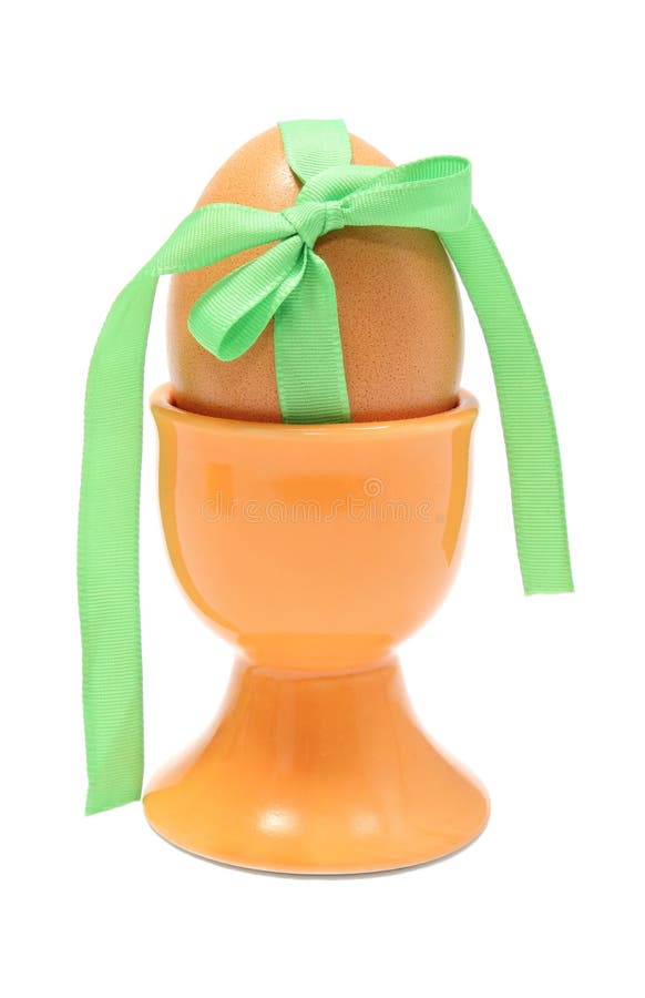 Paasei met groen lint in oranje kop Witte achtergrond stock foto Paasei met groen lint in oranje kop Witte achtergrond stock foto