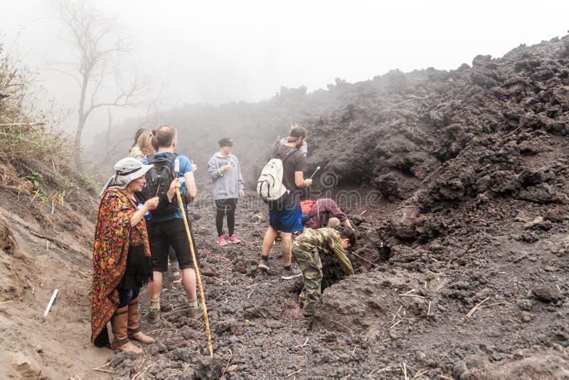 PACAYA, GUATEMALA - 28 MARS 2016 : Touristes rôtissant la guimauve au gisement de lave du volcan de Pacaya, Guatema image stock PACAYA, GUATEMALA - 28 MARS 2016 : Touristes rôtissant la guimauve au gisement de lave du volcan de Pacaya, Guatema image stock