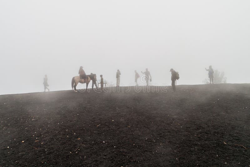 PACAYA, GUATEMALA - 28 MARZO 2016: Turisti che visitano il vulcano di Pacaya nella foschia, Guatema immagini stock libere da diritti PACAYA, GUATEMALA - 28 MARZO 2016: Turisti che visitano il vulcano di Pacaya nella foschia, Guatema immagini stock libere da diritti