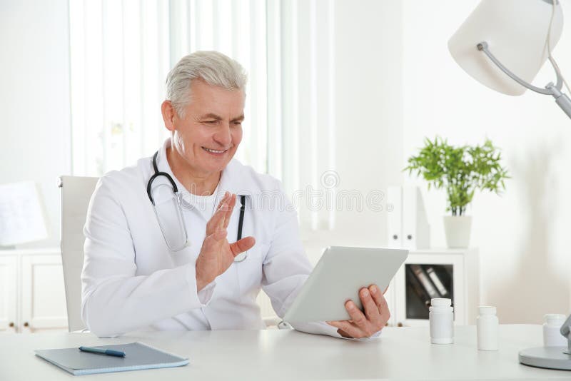 Paciente asesor del doctor que usa la charla video en la tableta imagen de archivo libre de regalías Paciente asesor del doctor que usa la charla video en la tableta imagen de archivo libre de regalías
