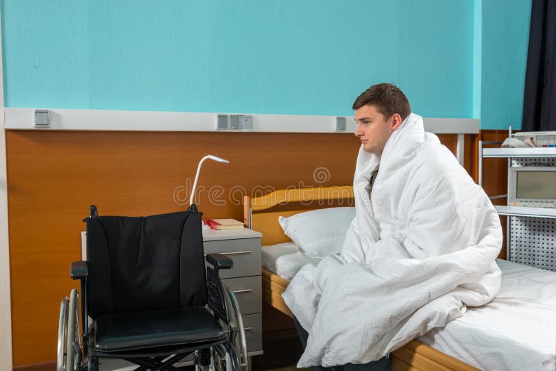 Paciente doente masculino que senta-se na cama de hospital coberta com a edredão imagens de stock Paciente doente masculino que senta-se na cama de hospital coberta com a edredão imagens de stock