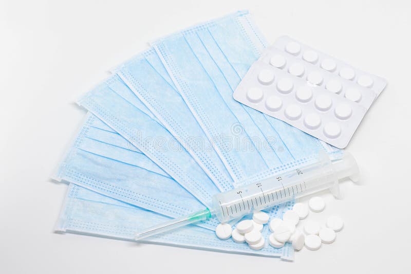 Medical kit from a mask, syringe and medicines to protect health. A pack of medical masks with a syringe and pills as a protection of diseases. Health care stock photography Medical kit from a mask, syringe and medicines to protect health. A pack of medical masks with a syringe and pills as a protection of diseases. Health care stock photography
