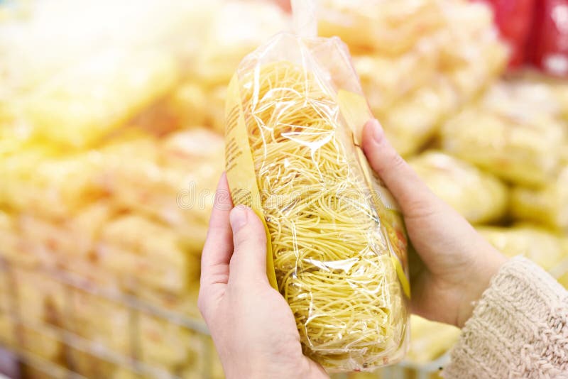 Pack of spaghetti in hands of buyer at store stock photos Pack of spaghetti in hands of buyer at store stock photos