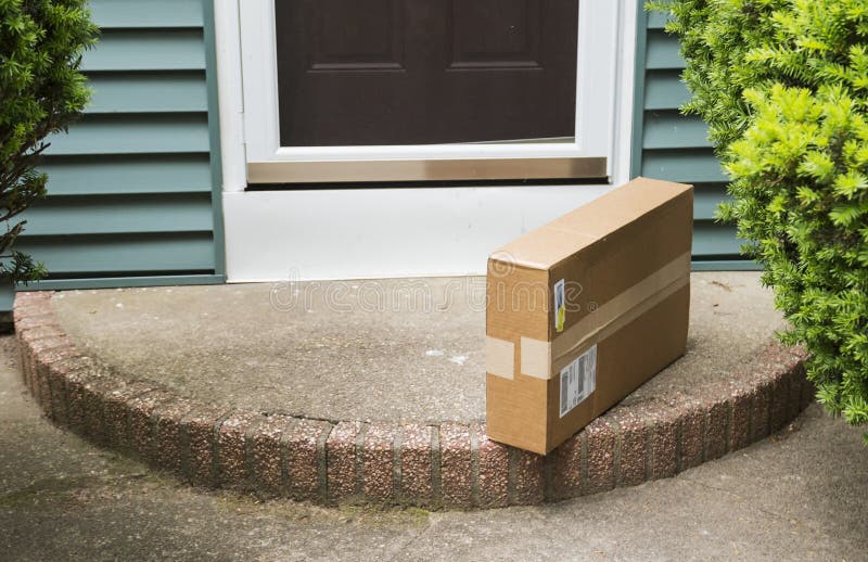 A brown cardboard box is left on the front stoop after being delivered while no one was home. A brown cardboard box is left on the front stoop after being delivered while no one was home.
