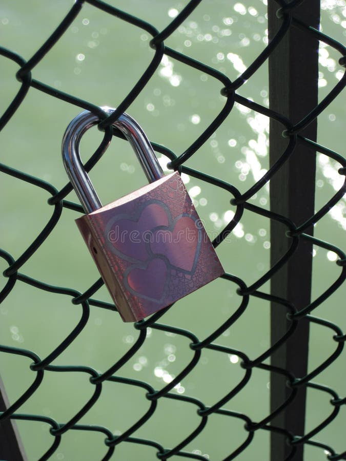 The padlock as a symbol of love is hanging on the railing of a bridge royalty free stock photo