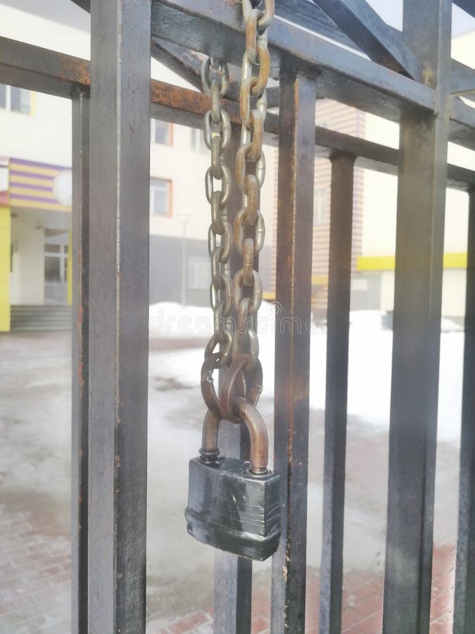 A Padlock on a Chain on a Gate Rewound with Electrical Tape. Stock