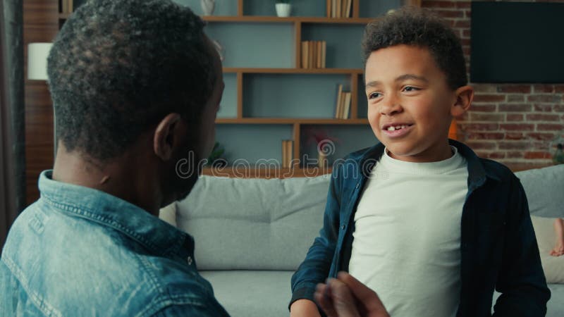 Padre adulto afroamericano padre emocional hablando con su hijo niño de etnia infantil riéndose charla con gestos divirtiéndose