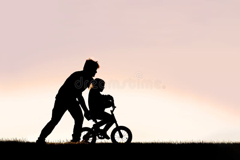 Padre aiuta il suo bambino a imparare a guidare in bicicletta con le ruote fotografia stock
