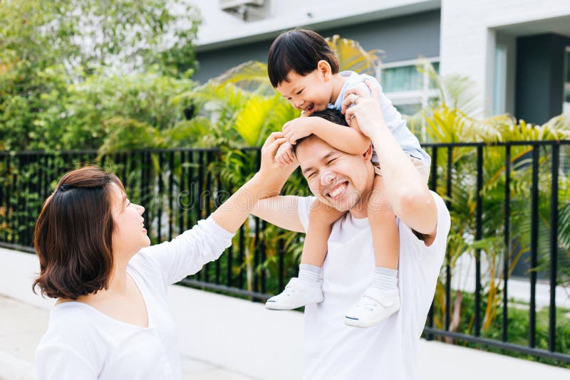 Padre asiatico sveglio che piggbacking suo figlio con la sua moglie nel parco Famiglia emozionante che spende tempo insieme alla immagine stock libera da diritti Padre asiatico sveglio che piggbacking suo figlio con la sua moglie nel parco Famiglia emozionante che spende tempo insieme alla immagine stock libera da diritti