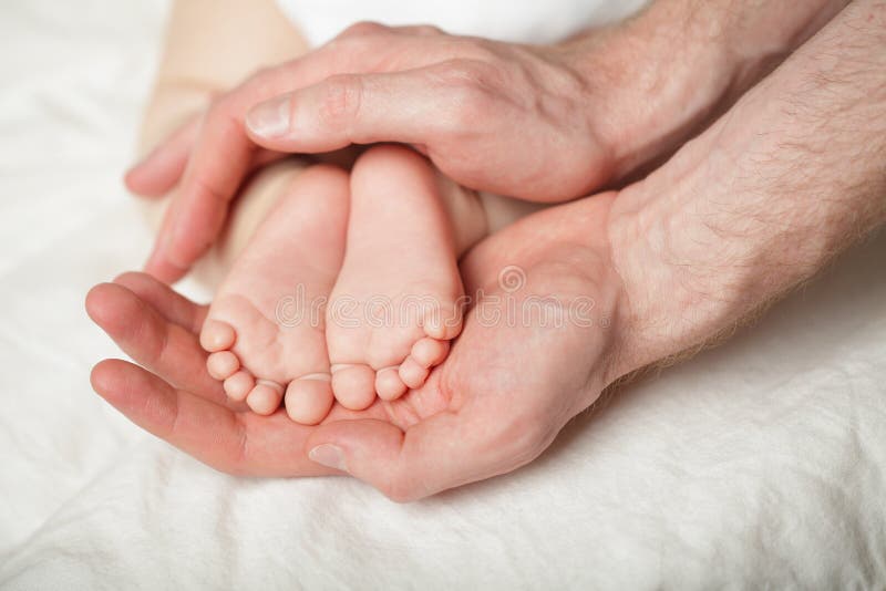 Padre che tiene i babyfeets neonati in sue mani su fondo bianco fotografia stock Padre che tiene i babyfeets neonati in sue mani su fondo bianco fotografia stock