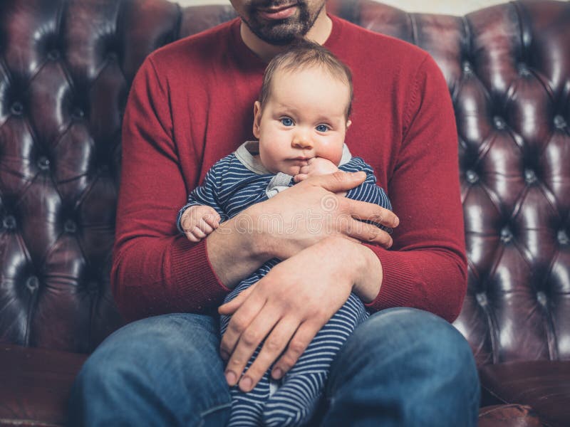 Padre con bebé en el sofá imagen de archivo