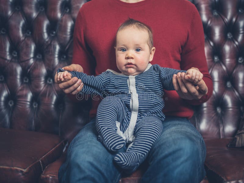 Padre con bebé en el sofá imagenes de archivo