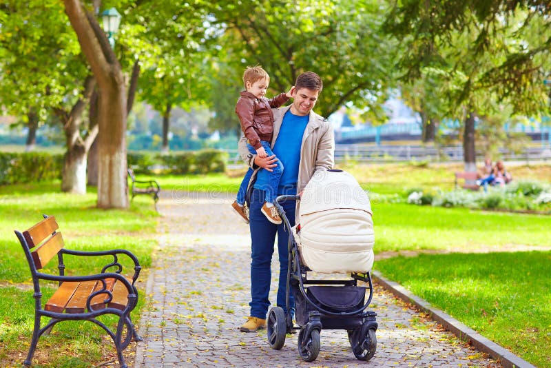 Padre con i bambini che camminano nel parco della città fotografie stock libere da diritti Padre con i bambini che camminano nel parco della città fotografie stock libere da diritti