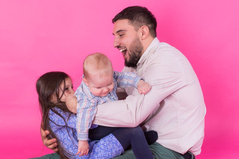 Padre con i bambini divertendosi sul fondo rosa fotografia stock Padre con i bambini divertendosi sul fondo rosa fotografia stock