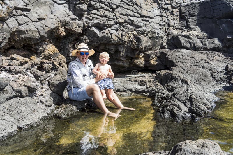 Padre con un figlio che si gode l'acqua nelle piscine naturali di charcones. lanzarote canarino spagna immagini stock libere da diritti