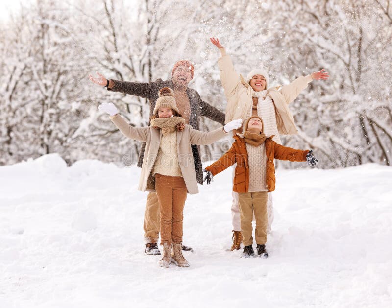 Padre di famiglia felice e bambini che gettano la neve in aria gioiscono dell'inverno in natura durante la nevicata giornata