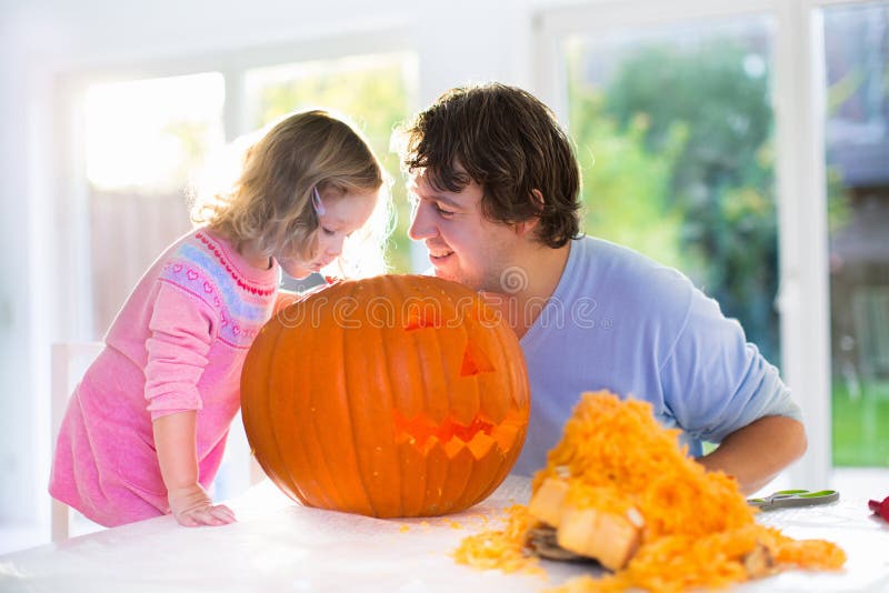 Padre e bambino che scolpiscono zucca per Halloween fotografia stock Padre e bambino che scolpiscono zucca per Halloween fotografia stock
