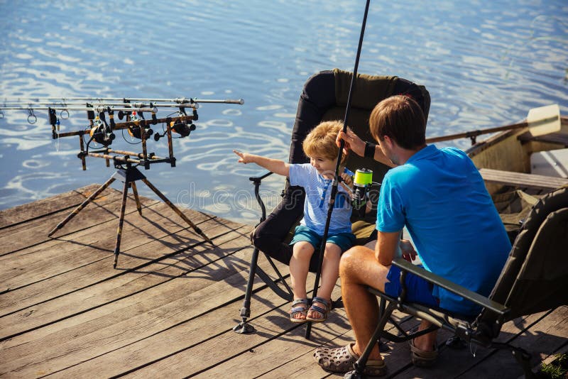 Padre e figlio che pescano insieme nel lago immagine stock Padre e figlio che pescano insieme nel lago immagine stock