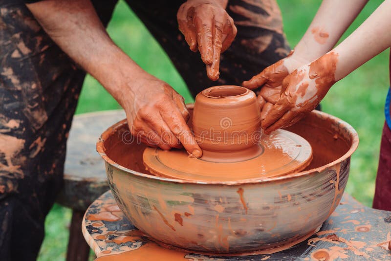 Father and son making ceramic pot. Family working on pottery wheel. Potters and child hands. Pottery workshop outside. Master teaching kid to creating on the pottery wheel. Craftsman`s hands and child. Father and son making ceramic pot. Family working on pottery wheel. Potters and child hands. Pottery workshop outside. Master teaching kid to creating on the pottery wheel. Craftsman`s hands and child