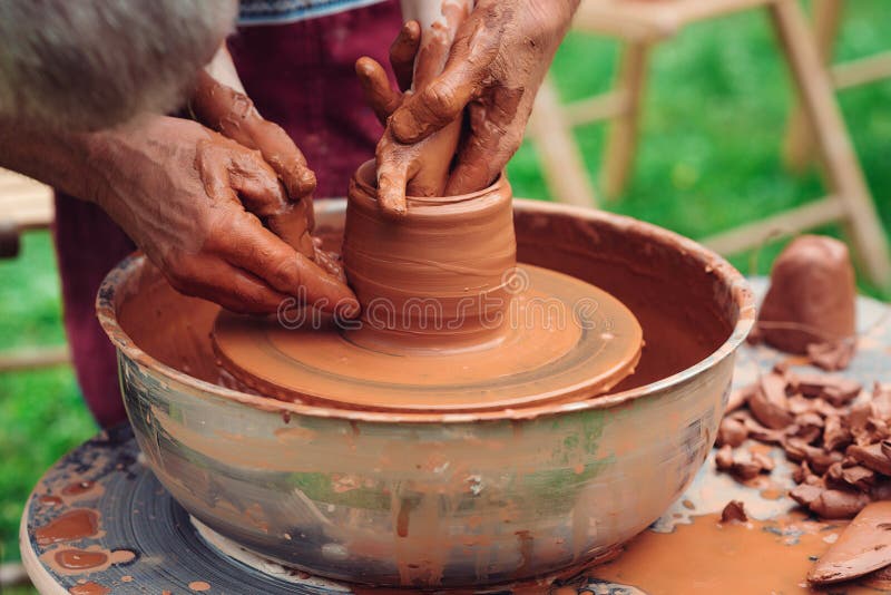 Father and son making ceramic pot. Family working on pottery wheel. Potters and child hands. Pottery workshop outside. Master teaching kid to creating on the pottery wheel. Craftsman`s hands and child. Father and son making ceramic pot. Family working on pottery wheel. Potters and child hands. Pottery workshop outside. Master teaching kid to creating on the pottery wheel. Craftsman`s hands and child