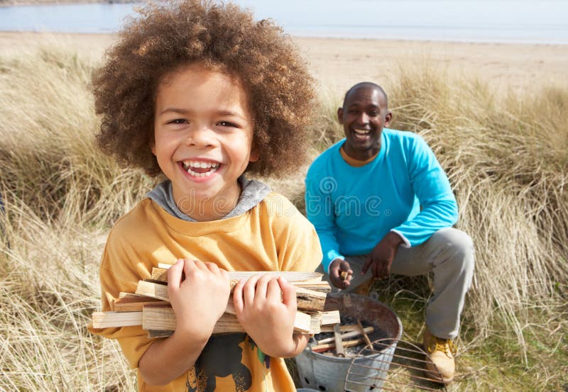 Padre e figlio che raccolgono legna da ardere sulla spiaggia fotografia stock libera da diritti Padre e figlio che raccolgono legna da ardere sulla spiaggia fotografia stock libera da diritti