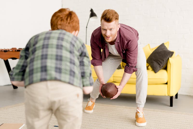 Padre e hijo pelirrojos sonrientes que juegan con la bola de rugbi fotografía de archivo libre de regalías