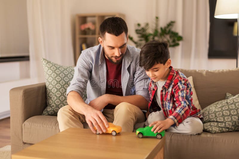Padre e hijo que juegan con los coches del juguete en casa imagenes de archivo Padre e hijo que juegan con los coches del juguete en casa imagenes de archivo