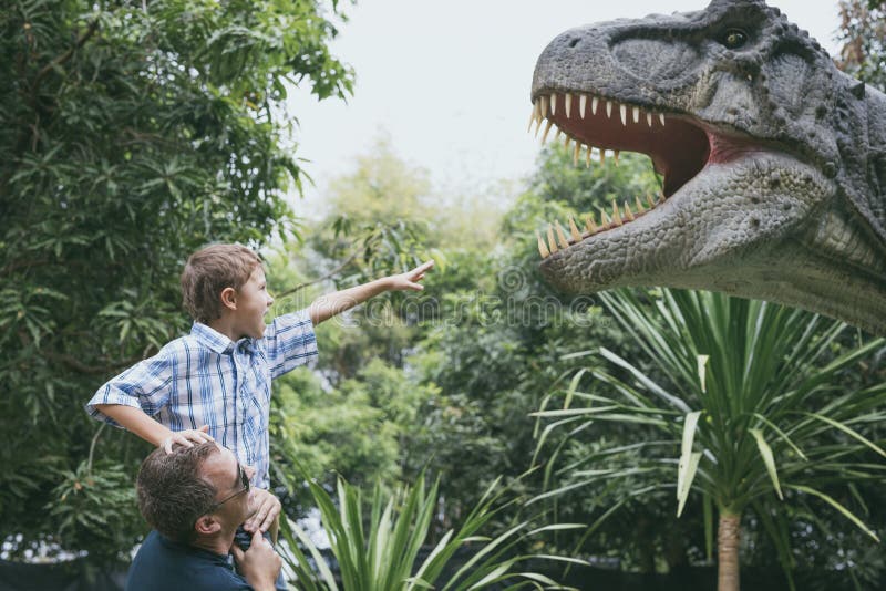 Padre e hijo que juegan en el parque de Dino de la aventura fotografía de archivo Padre e hijo que juegan en el parque de Dino de la aventura fotografía de archivo