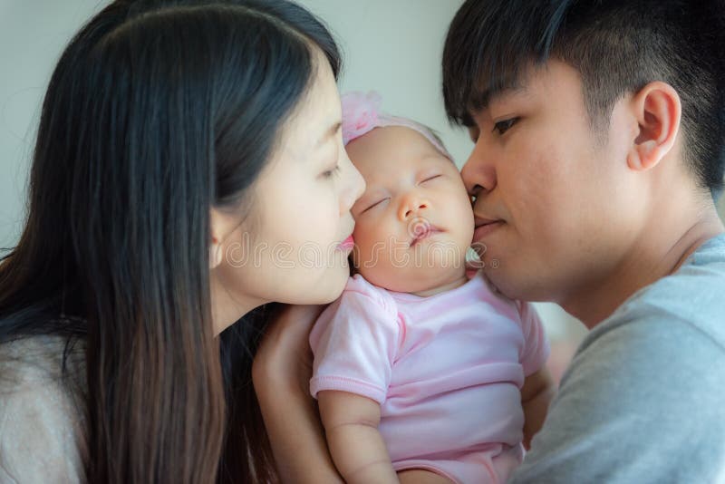 Padre e madre che bacia un piccolo bambino, paternità, famiglia concentrata fotografie stock libere da diritti Padre e madre che bacia un piccolo bambino, paternità, famiglia concentrata fotografie stock libere da diritti