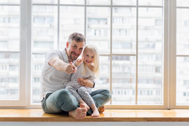 Padre feliz con hija apuntando con los dedos contra la ventana imagen de archivo libre de regalías Padre feliz con hija apuntando con los dedos contra la ventana imagen de archivo libre de regalías