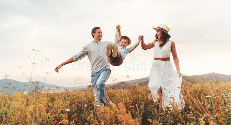 Padre feliz de la familia del hijo de la madre y del niño en puesta del sol de la naturaleza imagen de archivo libre de regalías Padre feliz de la familia del hijo de la madre y del niño en puesta del sol de la naturaleza imagen de archivo libre de regalías