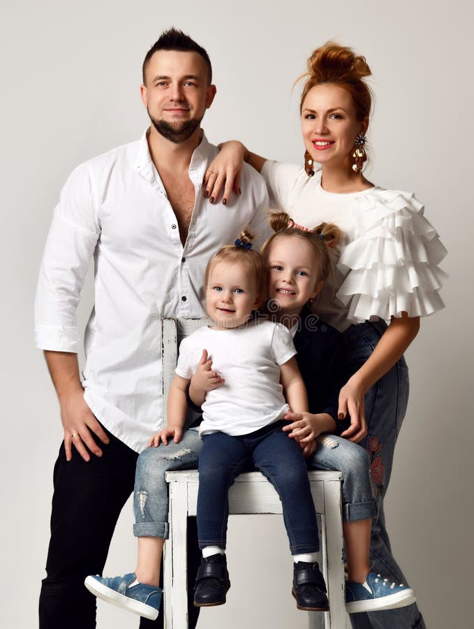 Padre feliz de la madre de la familia y dos muchachas de la hija que sonríen en estudio gris foto de archivo Padre feliz de la madre de la familia y dos muchachas de la hija que sonríen en estudio gris foto de archivo