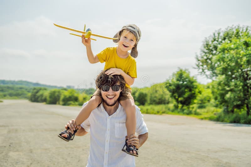 Padre feliz e hijo que juegan con el aeroplano del juguete contra viejo fondo de la pista El viajar con concepto de los niños fotografía de archivo libre de regalías Padre feliz e hijo que juegan con el aeroplano del juguete contra viejo fondo de la pista El viajar con concepto de los niños fotografía de archivo libre de regalías