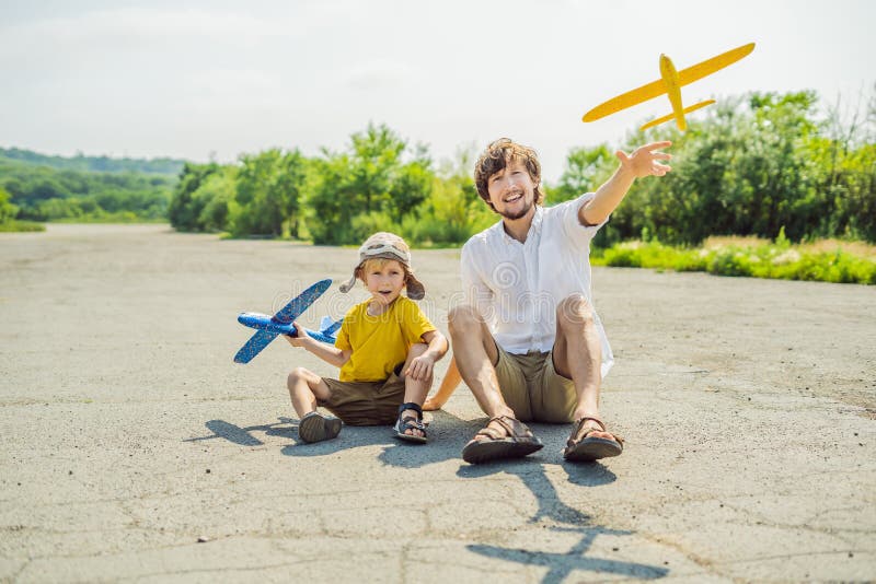 Padre feliz e hijo que juegan con el aeroplano del juguete contra viejo fondo de la pista El viajar con concepto de los niños imágenes de archivo libres de regalías Padre feliz e hijo que juegan con el aeroplano del juguete contra viejo fondo de la pista El viajar con concepto de los niños imágenes de archivo libres de regalías