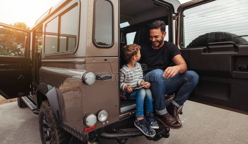 Padre feliz e hijo que se sientan en la parte posterior del coche foto de archivo Padre feliz e hijo que se sientan en la parte posterior del coche foto de archivo