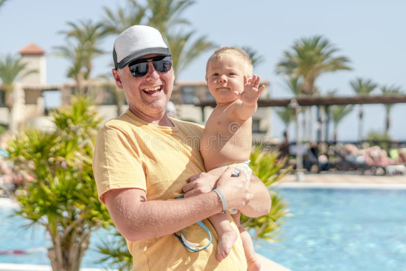 Padre feliz que detiene al hijo alegre durante vacaciones tropicales foto de archivo libre de regalías Padre feliz que detiene al hijo alegre durante vacaciones tropicales foto de archivo libre de regalías