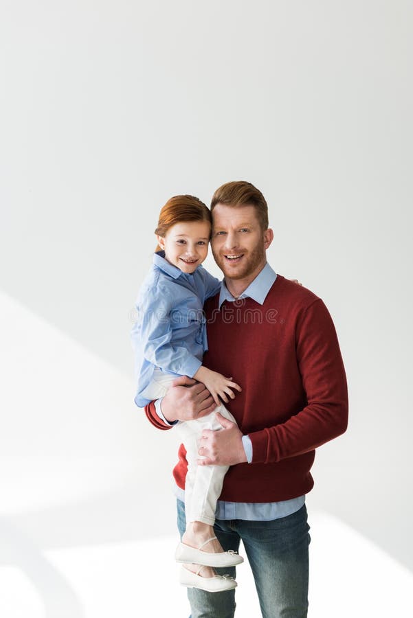 Padre feliz que lleva a la pequeña hija adorable y que sonríe en la cámara fotos de archivo libres de regalías