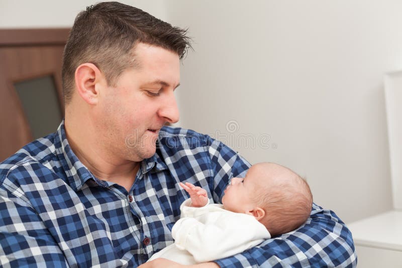 Padre fiero che tiene il suo neonato in mani fotografie stock Padre fiero che tiene il suo neonato in mani fotografie stock