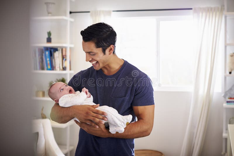 Padre ispano fiero che tiene il suo bambino di quattro mesi a casa, visto dalla entrata fotografia stock libera da diritti