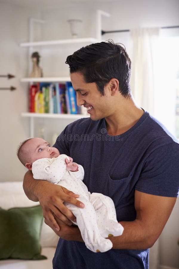 Padre ispano fiero che tiene il suo bambino di quattro mesi a casa, vita su, verticale fotografie stock