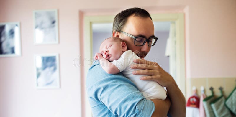 Padre joven que detiene al hijo recién nacido del bebé en sus brazos foto de archivo libre de regalías Padre joven que detiene al hijo recién nacido del bebé en sus brazos foto de archivo libre de regalías