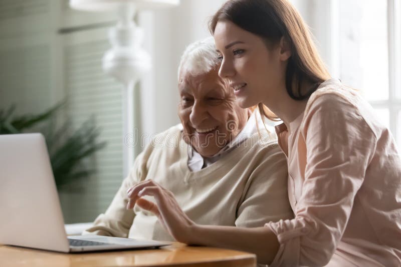 Padre maduro sonriente e hija adulta usando juntos una laptop imagen de archivo