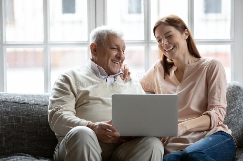 Padre maduro sonriente e hija mayor usando laptop fotografía de archivo