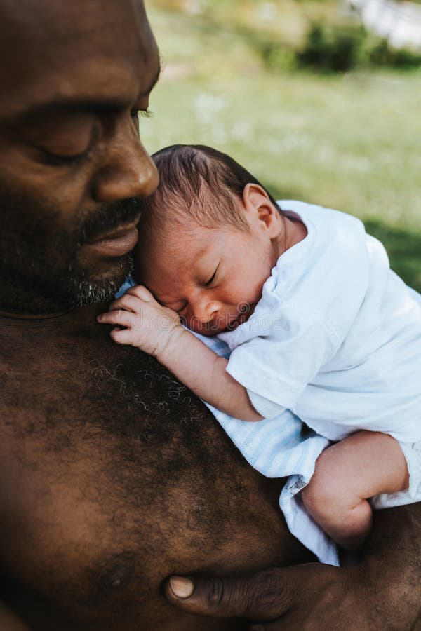 Padre nero che tiene il suo neonato addormentato della corsa mista