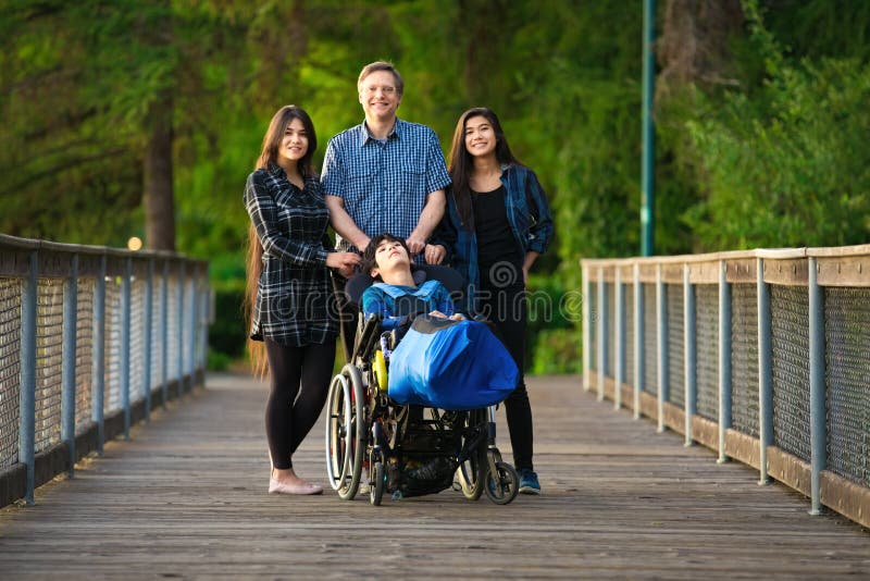 Padre in piedi con bambini nati su un ponte di legno, speciali necessità