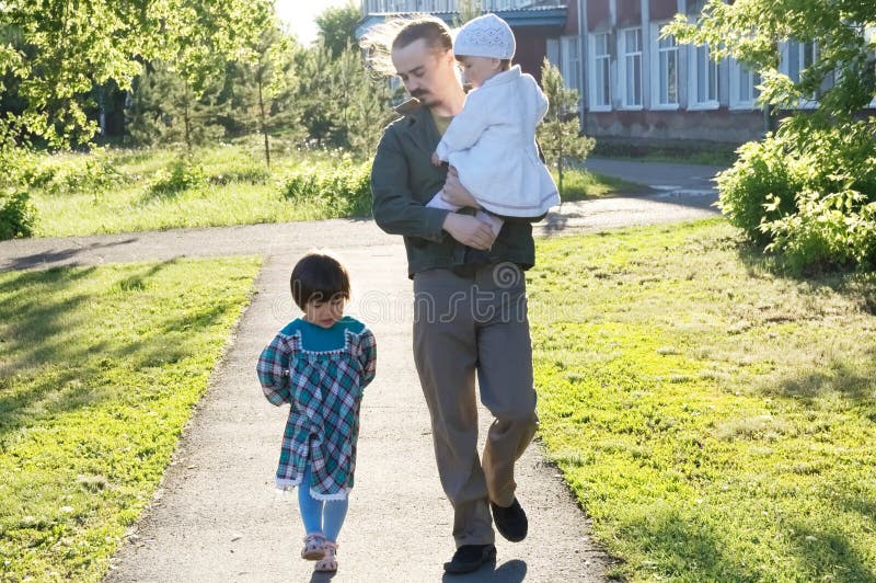 Padre que camina con las hijas en el día soleado papá y muchachas que enlazan la relación papá feliz con dos niños en el parque a fotografía de archivo libre de regalías Padre que camina con las hijas en el día soleado papá y muchachas que enlazan la relación papá feliz con dos niños en el parque a fotografía de archivo libre de regalías