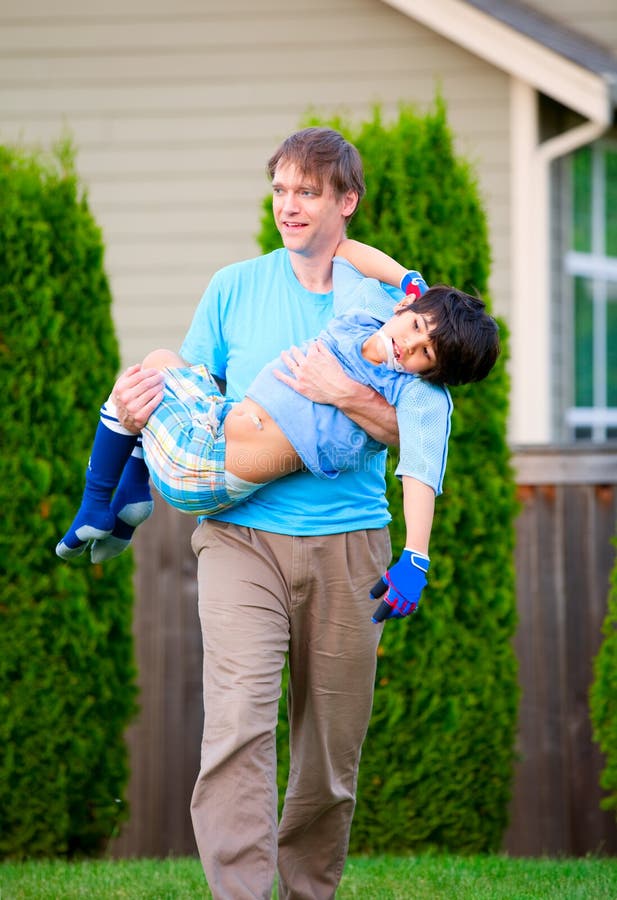 Padre que lleva al hijo inhabilitado al aire libre fotografía de archivo libre de regalías Padre que lleva al hijo inhabilitado al aire libre fotografía de archivo libre de regalías